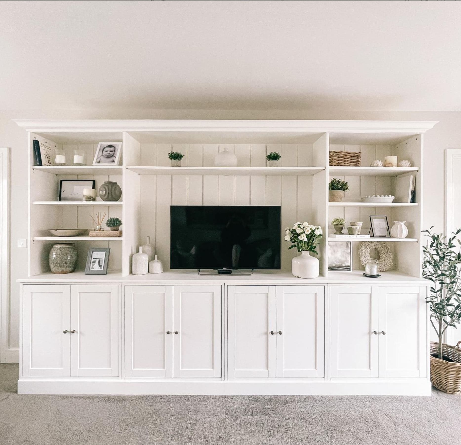 Four white IKEA Havsta cabinets with a built-in TV area and tongue-and-groove planking.