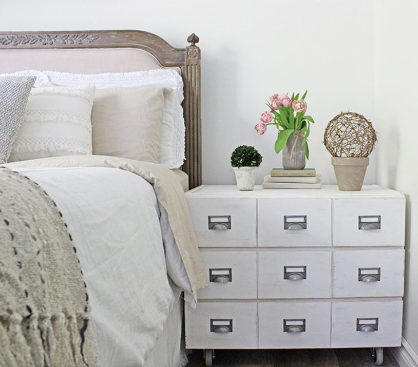 An IKEA hack card catalog nightstand with various décor on top.