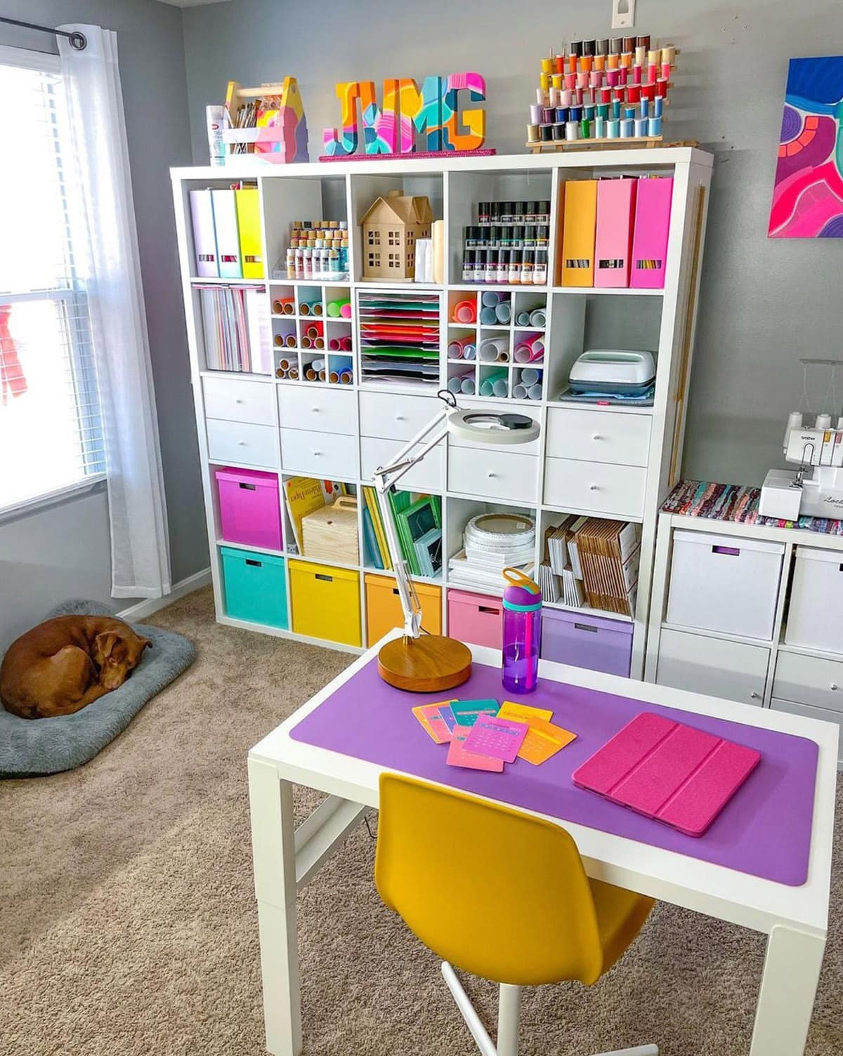 IKEA Kallax 5x5 white cube unit organized with colorful craft supplies in a craft room.