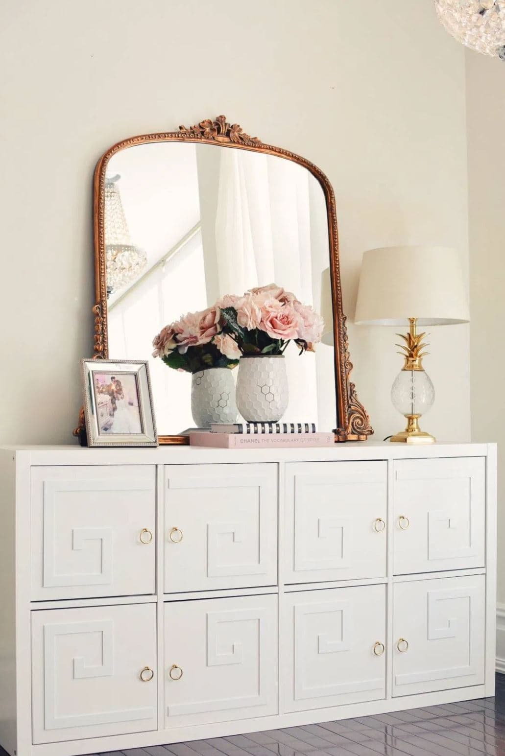 A DIY IKEA hack white dresser with geometric details and brass ring pulls.