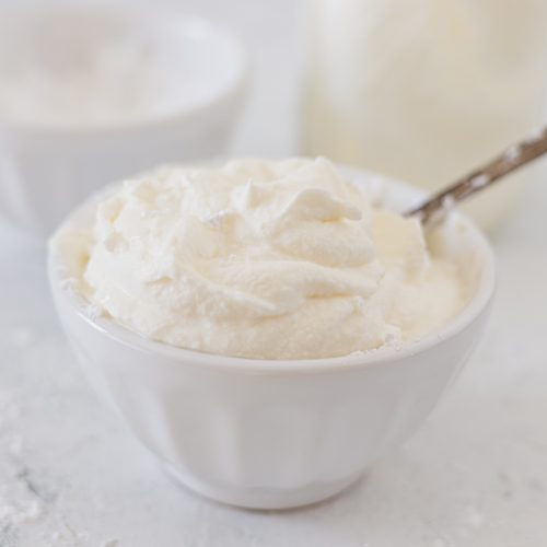 A white bowl filled with fresh whipped cream.