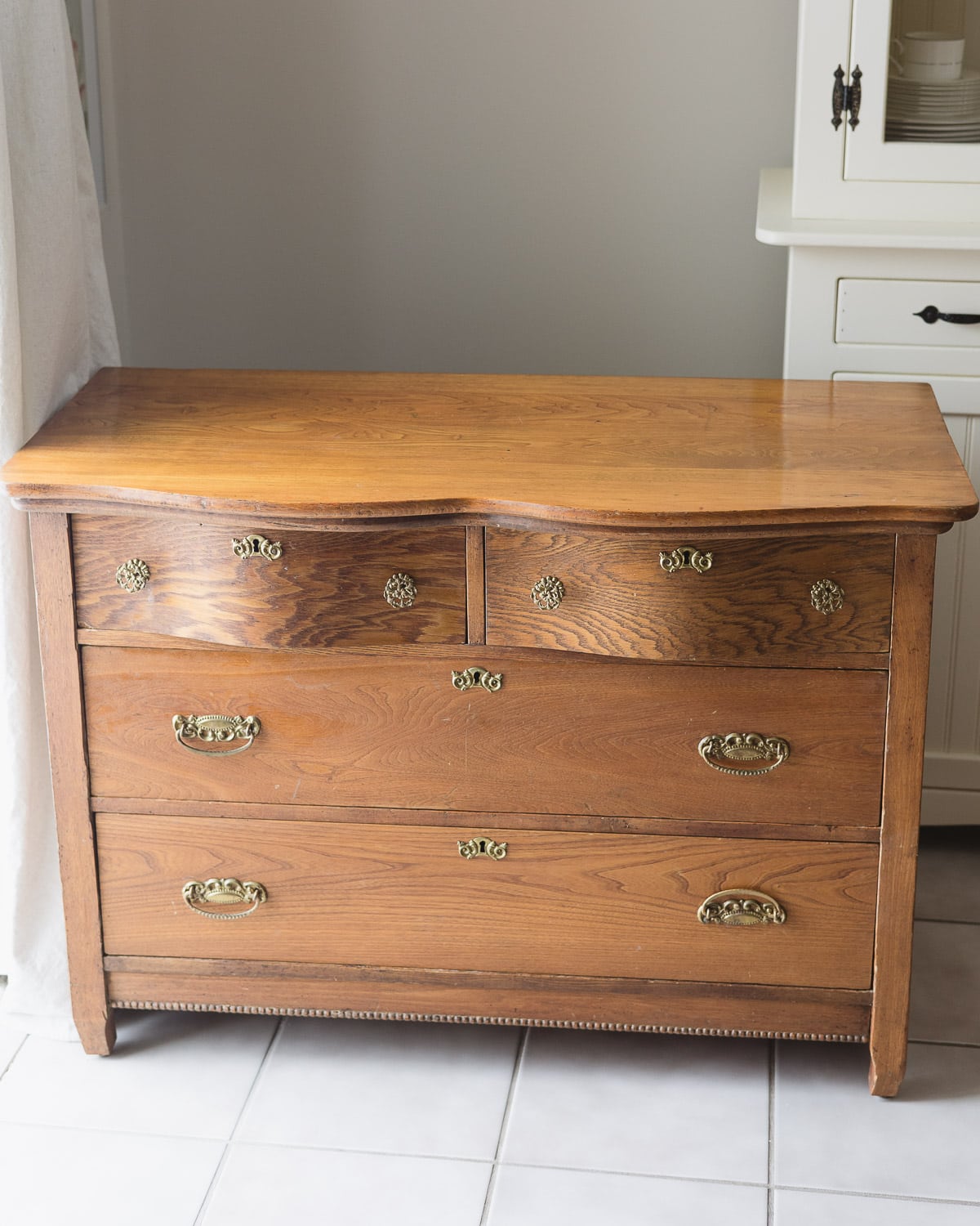 An old wooden dresser with brassy knobs, pulls, and keyholes.