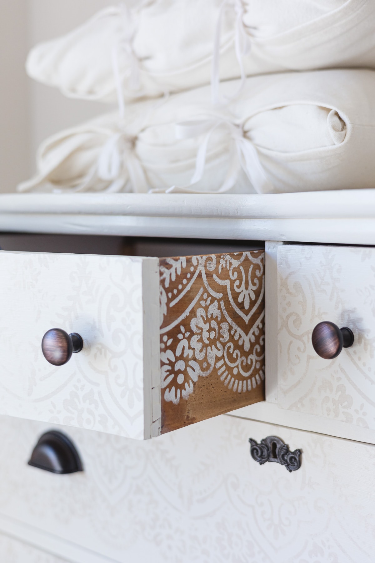 A drawer of a painted dresser pulled out to reveal white stenciling on the wood interior.