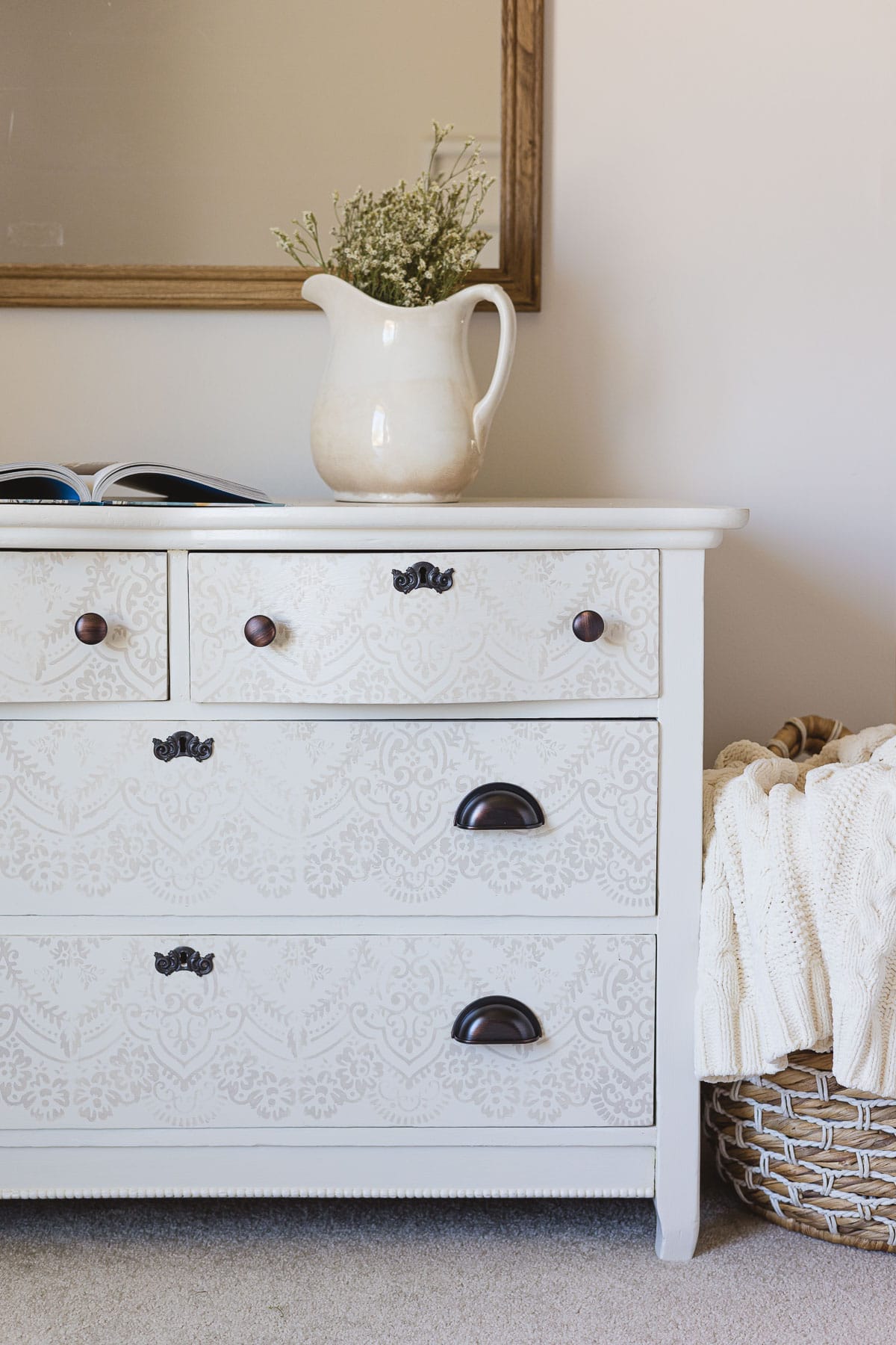 A white painted-and-stenciled dresser with oil-rubbed bronze hardware.