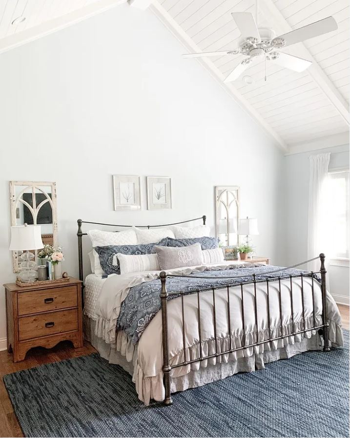 A blue and white bedroom with a planked ceiling with white beams and a ceiling fan.