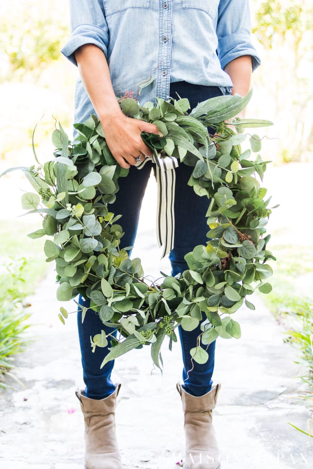 A woman holding a handmade eucalyptus wreath.