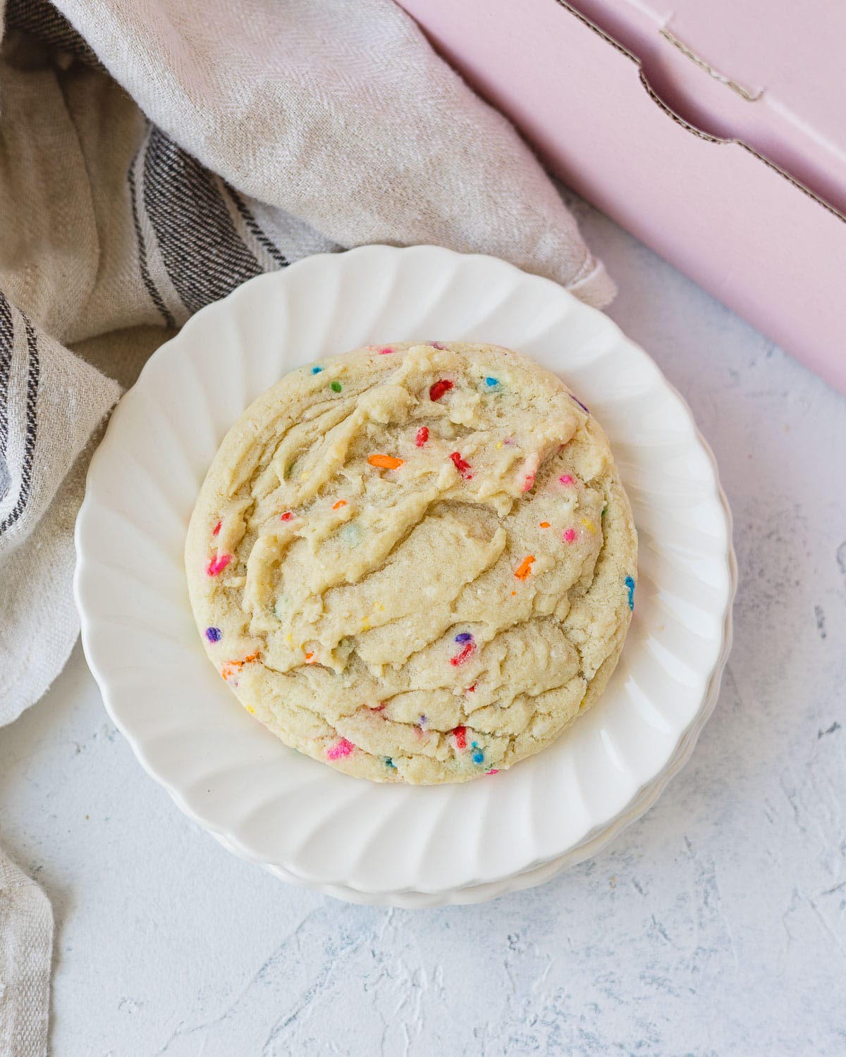 A funfetti sugar cookie on a stack of two small plates.