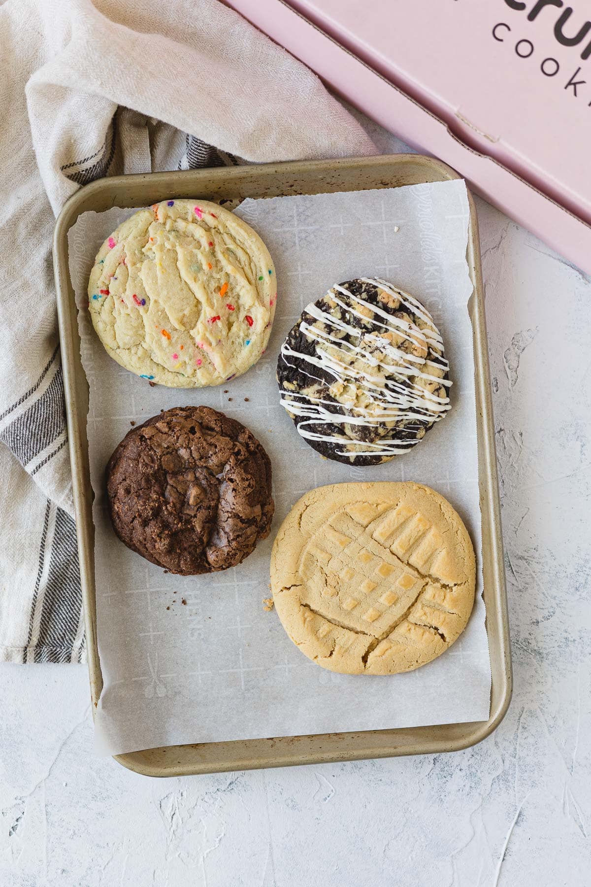 Four Crumbl Cookies on a parchment paper lined baking sheet.