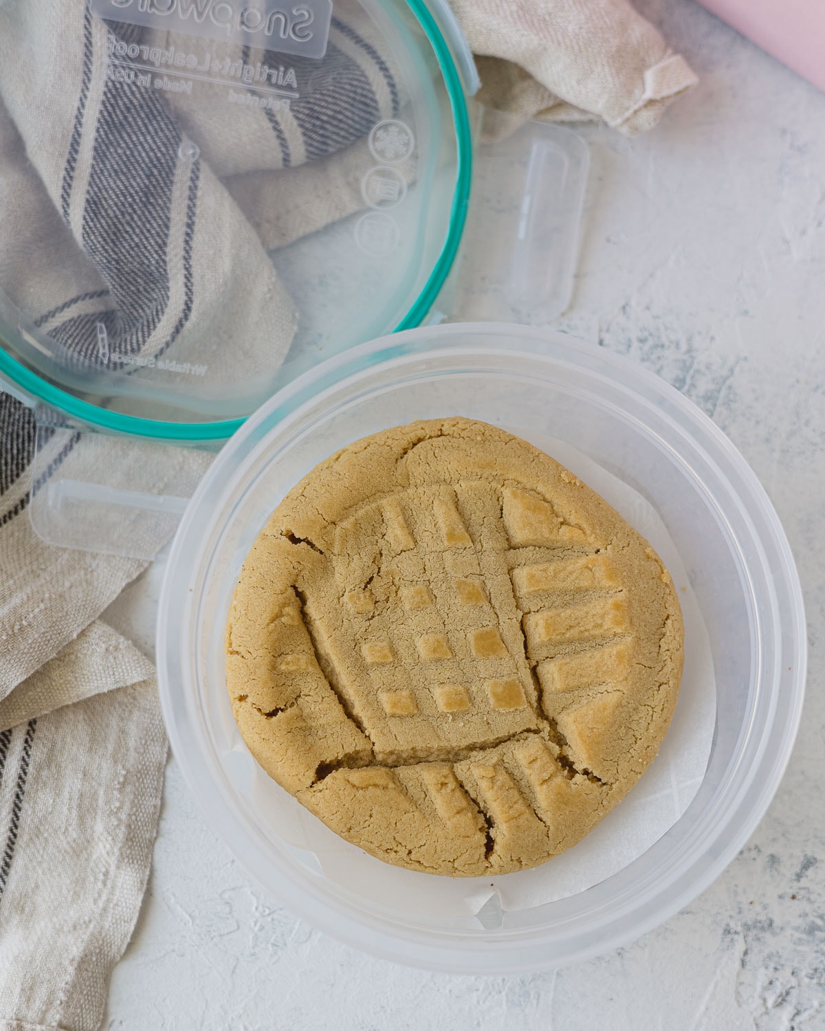 A peanut butter cookie in a snapware container with the lid removed.