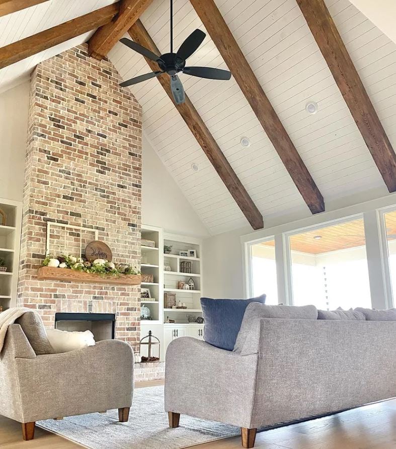 A white vaulted and planked ceiling with large wooden beams in a modern farmhouse living room.