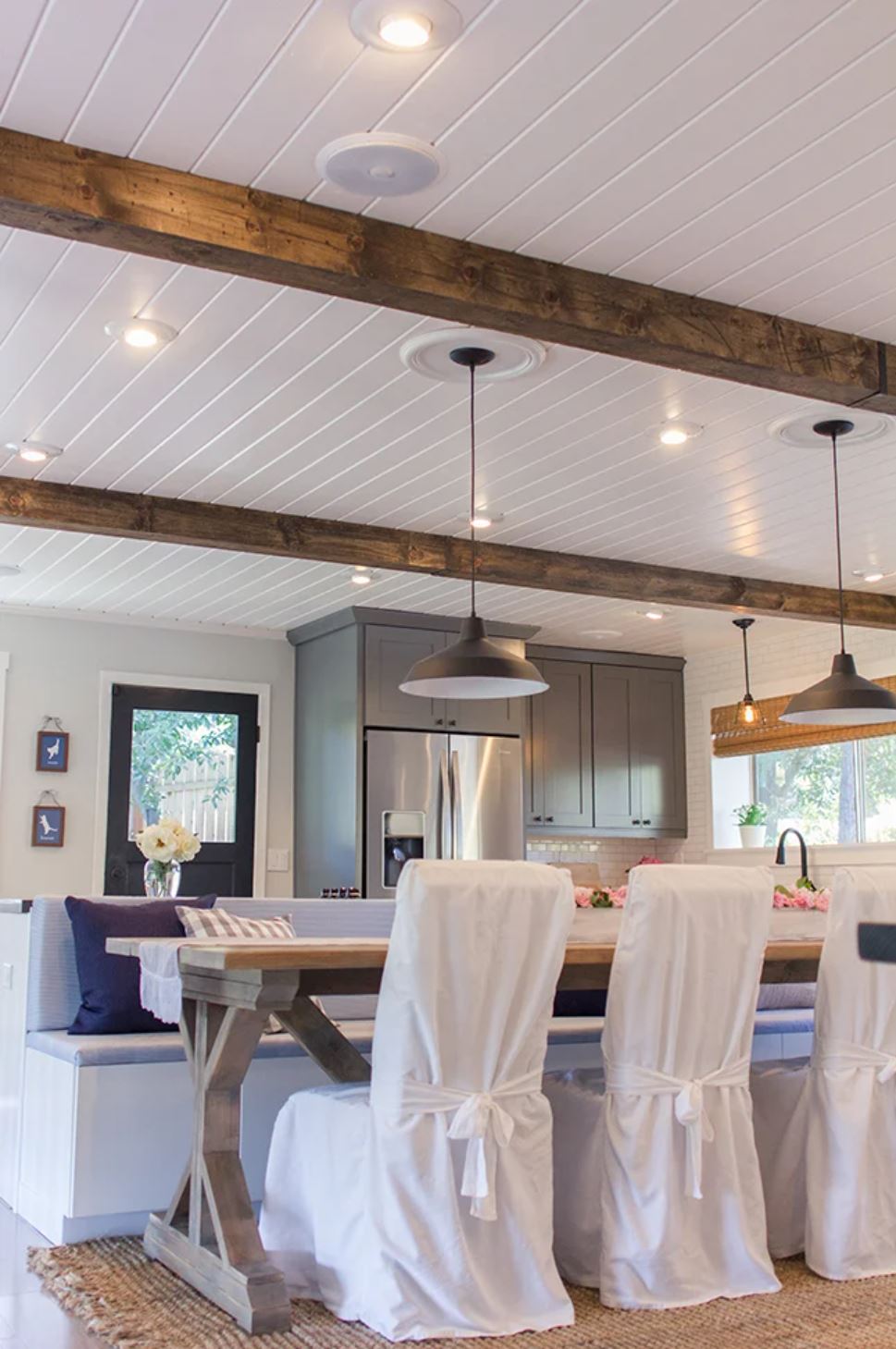 A white shiplap ceiling with beams in a modern farmhouse dining room.