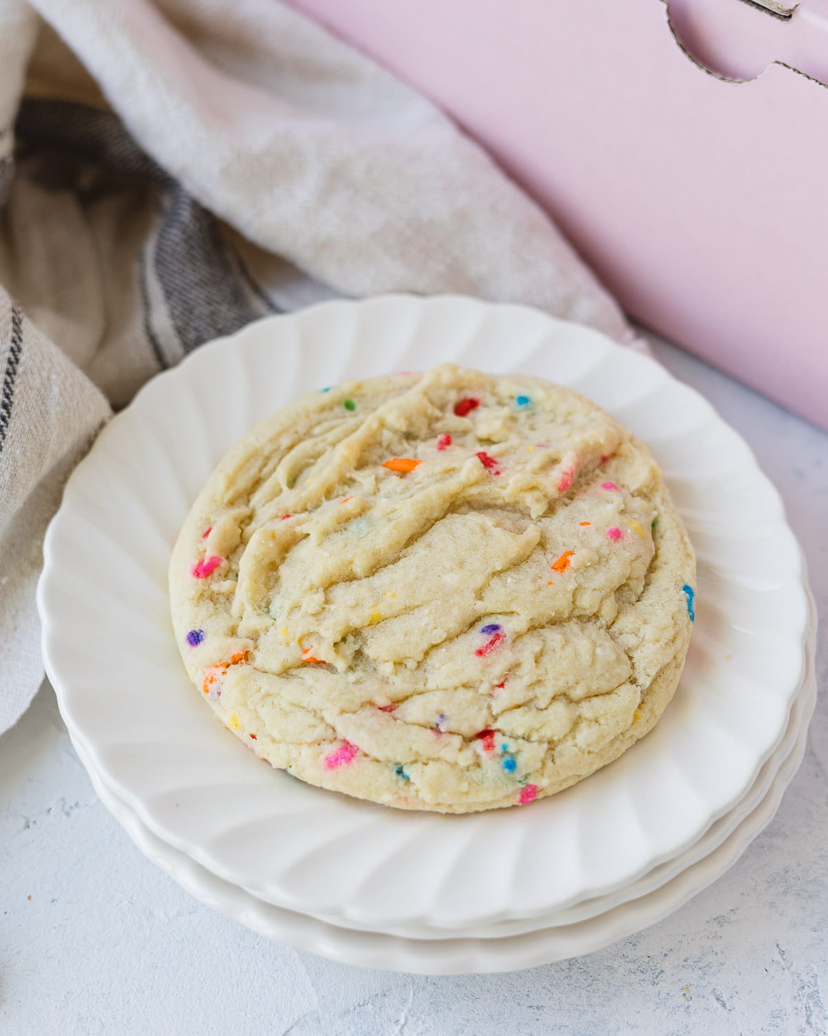 A funfetti sugar cookie on a stack of two small plates.