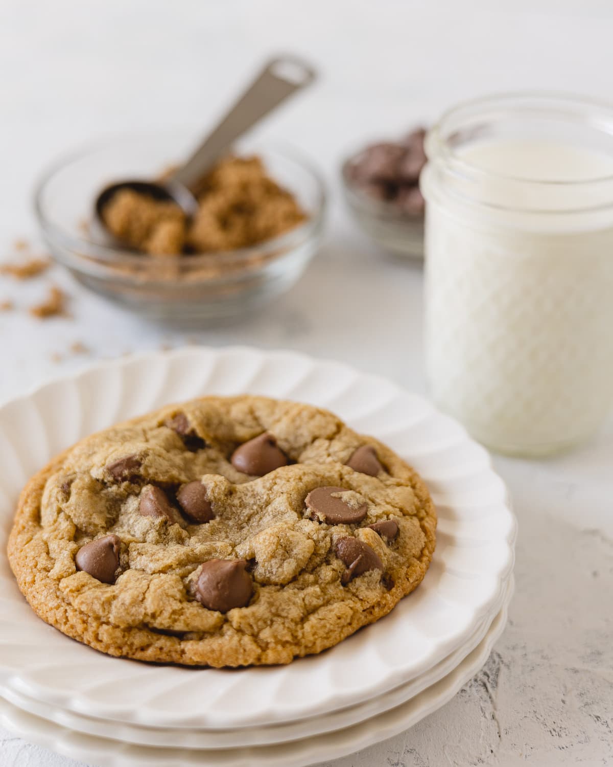 A milk chocolate cookie on a stack of white scalloped plates.