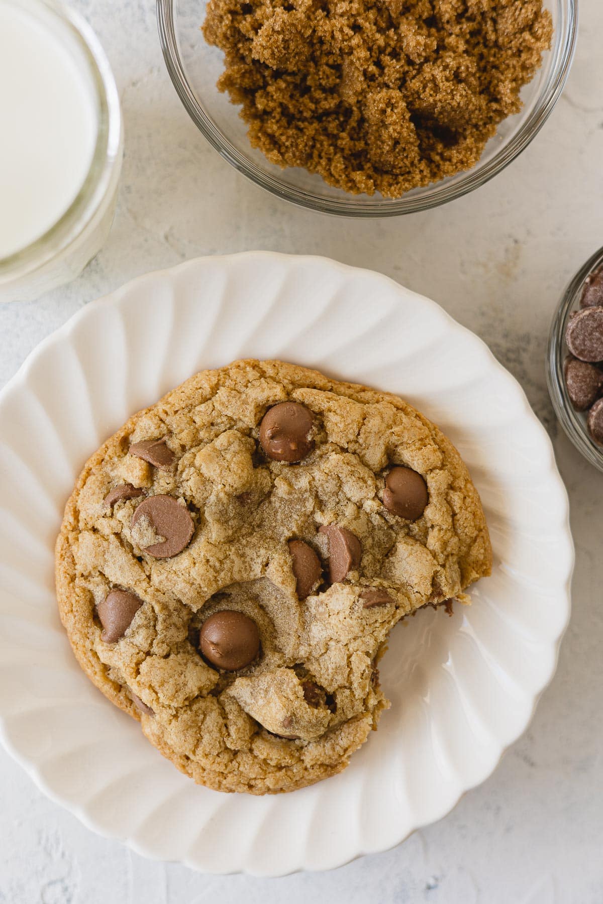 A large chocolate chip cookie with a bite removed.