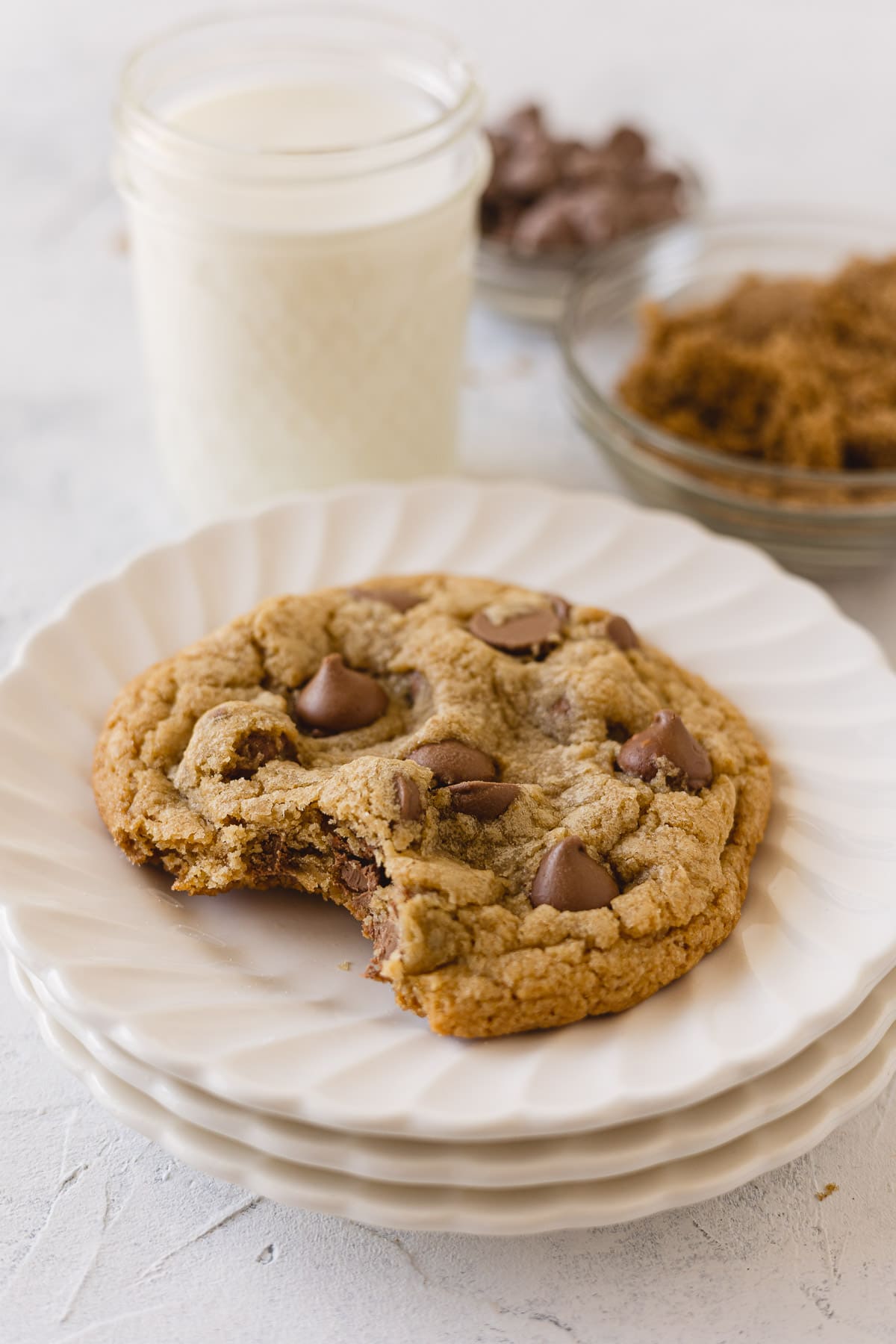 A chocolate chip cookie made with milk chocolate chips on a stack of small plates.