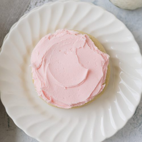Swirls of homemade pink buttercream on a sugar cookie.