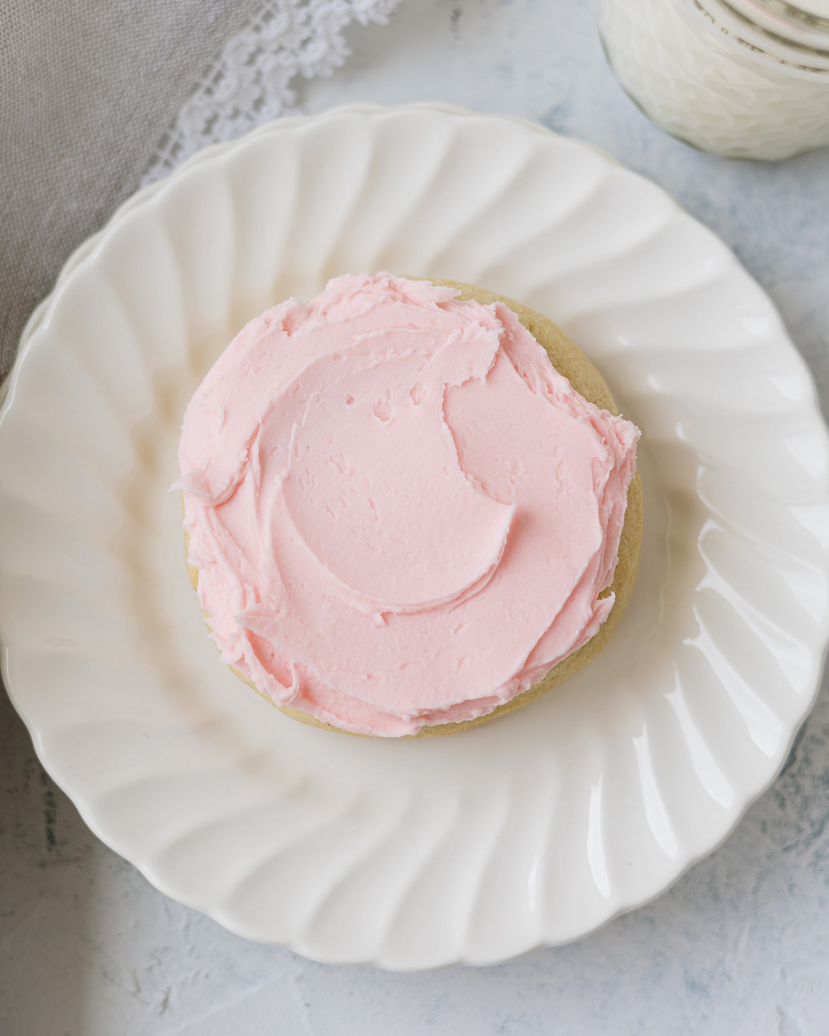 Swirls of homemade pink buttercream on a sugar cookie.