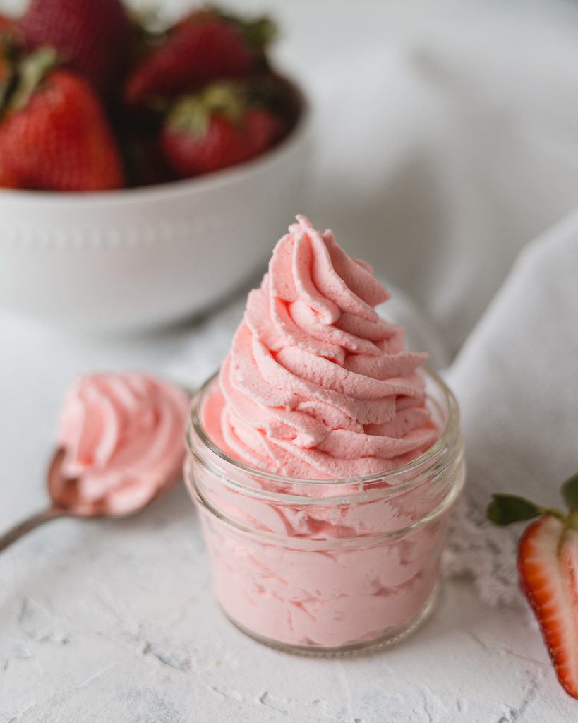 A mason jar swirled with piped pink whipped cream.