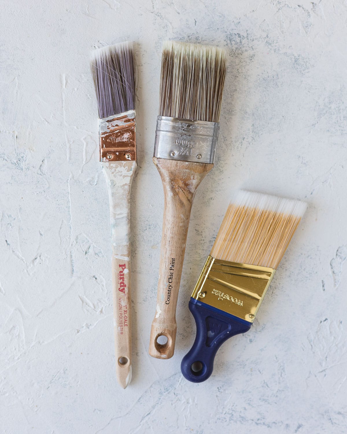 Three paint brushes on a rustic surface.