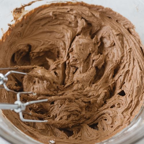 A bowl of chocolate buttercream with beaters.