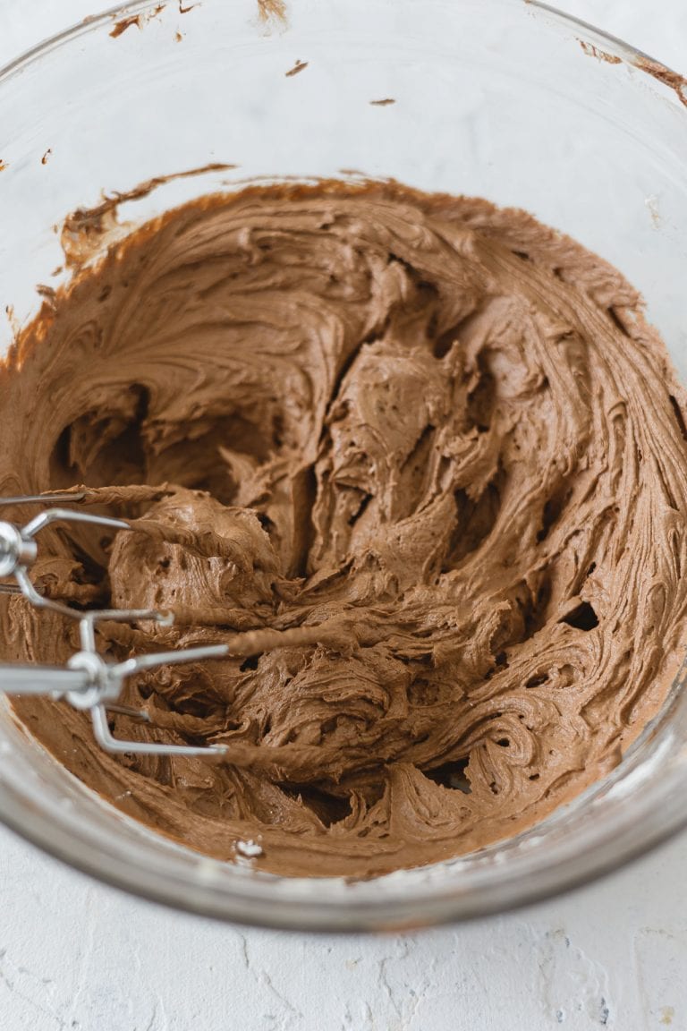 A bowl of chocolate buttercream with beaters.