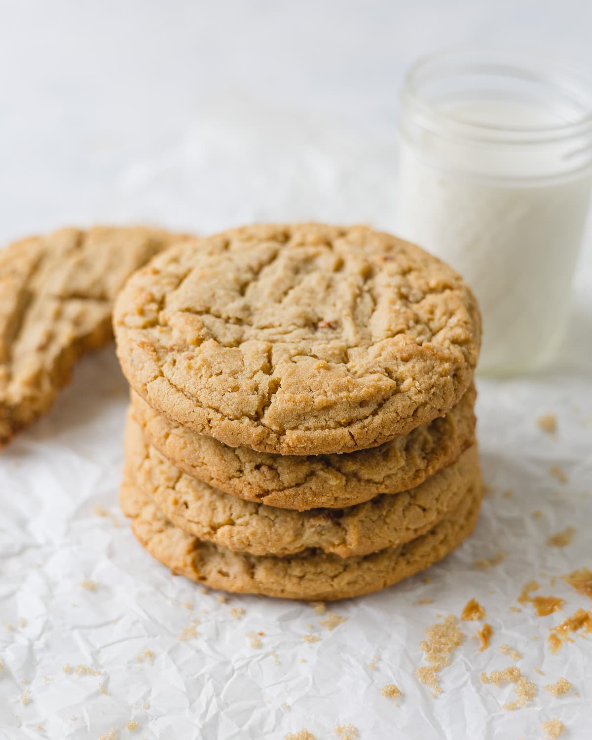 A stack of large Crumbl Classic Peanut Butter Cookies and a glass of milk.