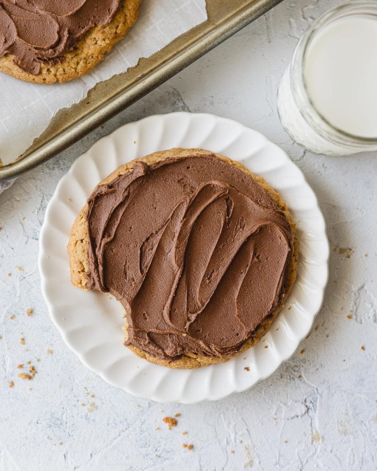 A chocolate-frosted peanut butter bar cookie with a bite removed on a white plate.