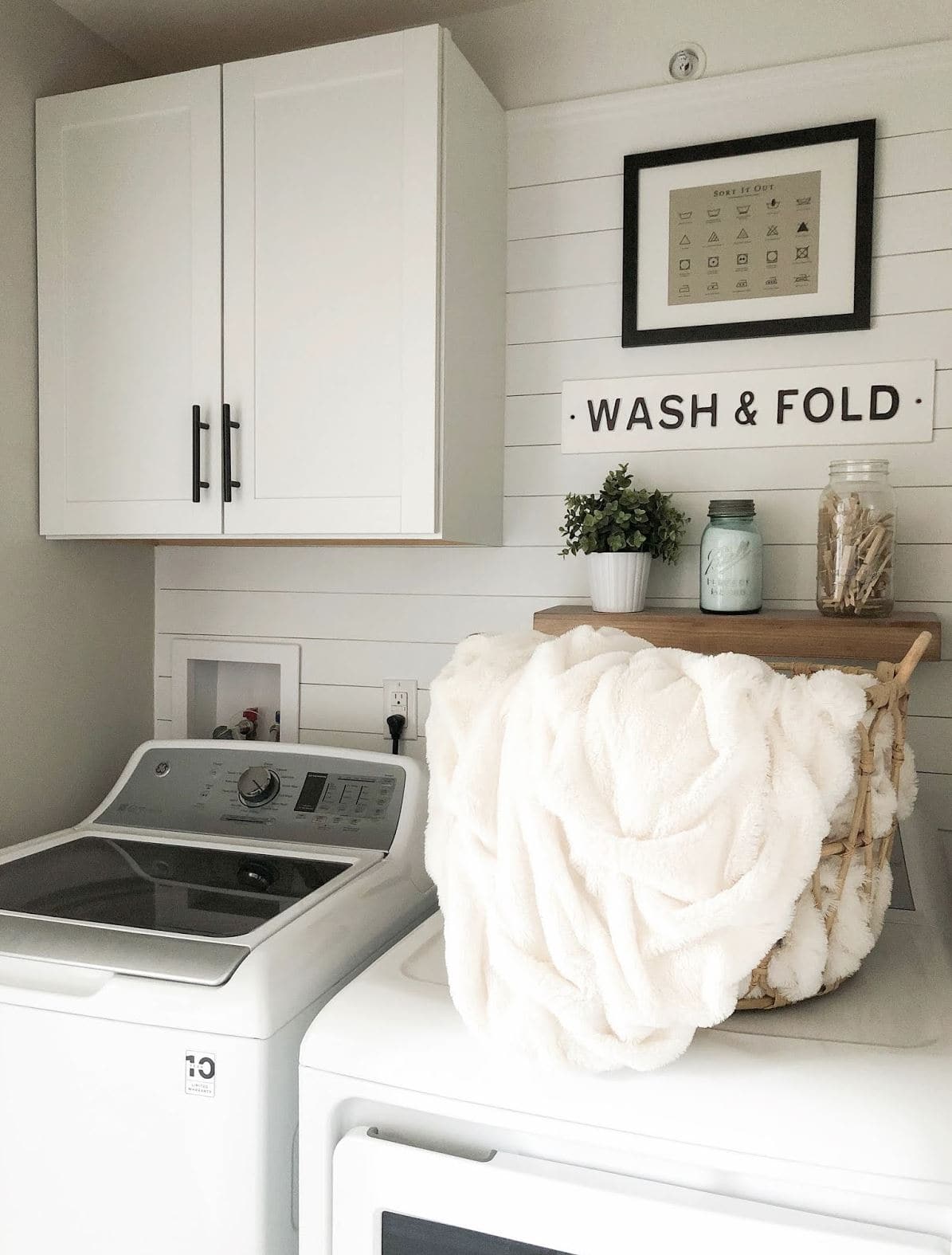 A farmhouse style laundry room with shiplap and a "wash & fold" sign.