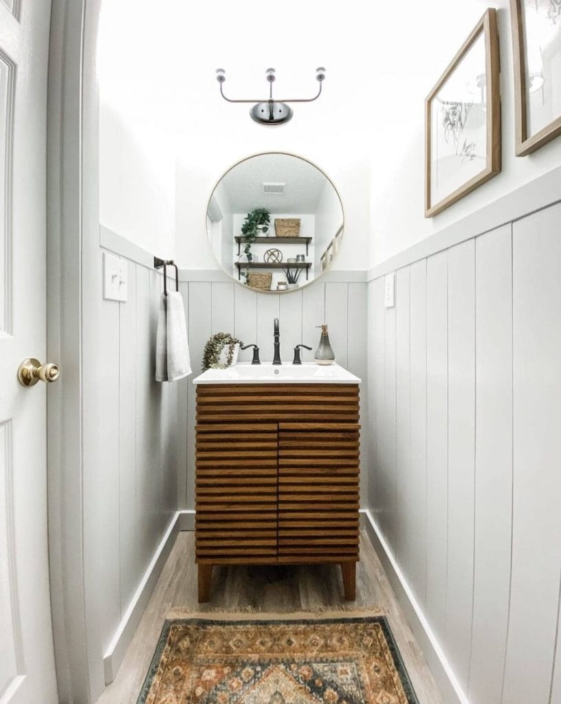 A small powder room with vertical shiplap on the walls, a modern wooden sink, and a mirror.
