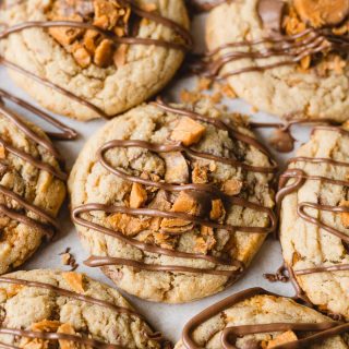 Crumbl copycat Butterfinger cookies with drizzles of milk chocolate.