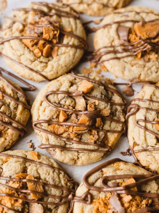 Crumbl copycat Butterfinger cookies with drizzles of milk chocolate.