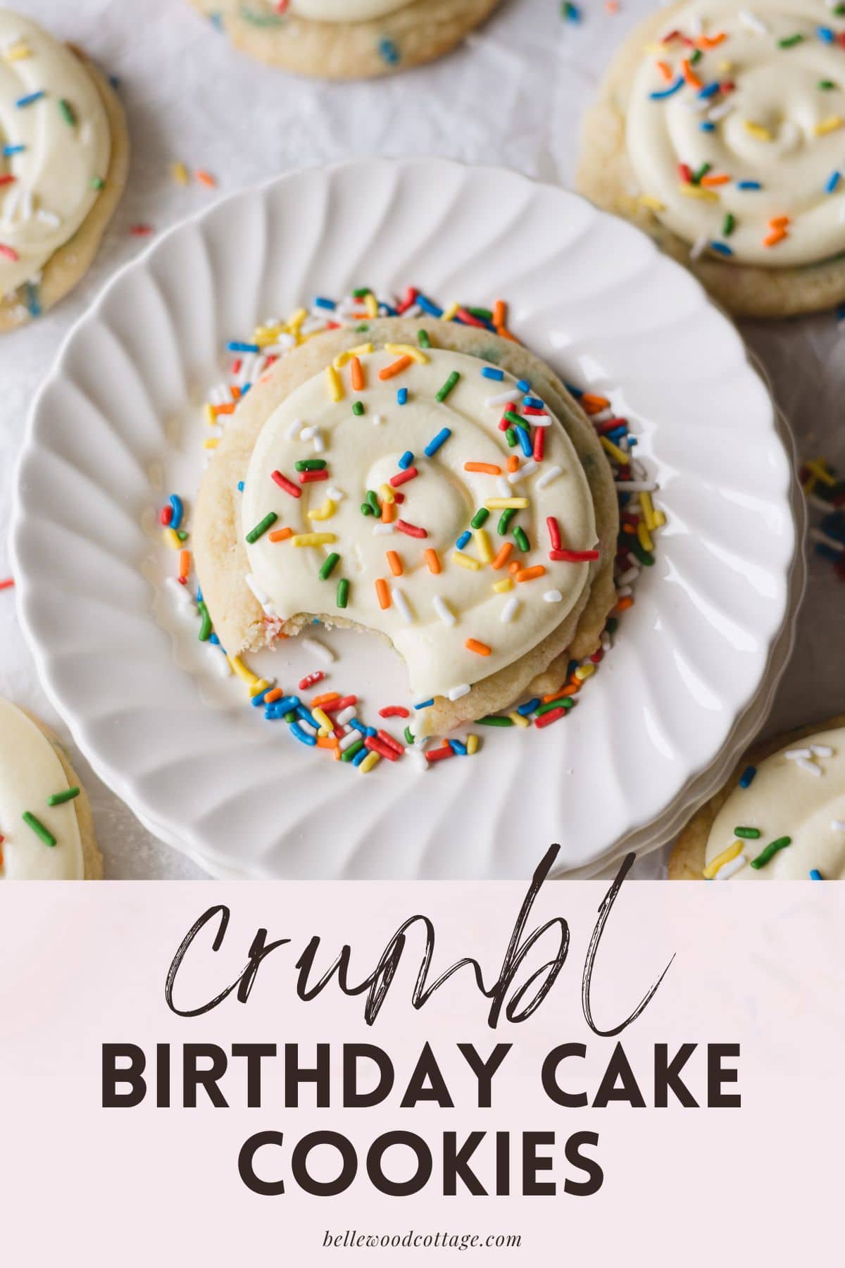 A frosted funfetti cookie topped with sprinkles with a bite removed and the words, "Crumbl Birthday Cake Cookies."