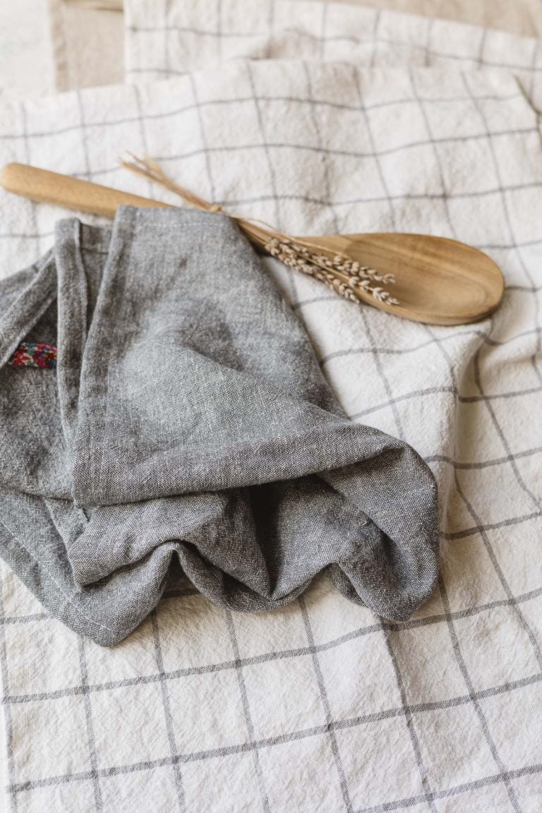 A handmade white linen towel with a gray grid design and a handmade blue-gray linen towel.