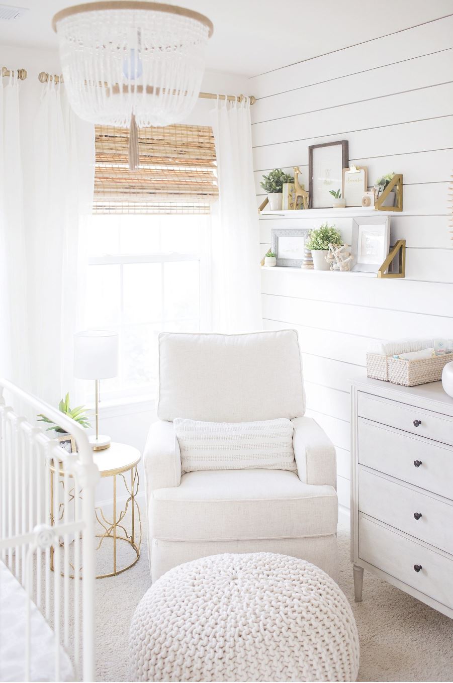 A gender neutral baby nursery with a shiplap accent wall, cozy recliner, crib, and dresser.
