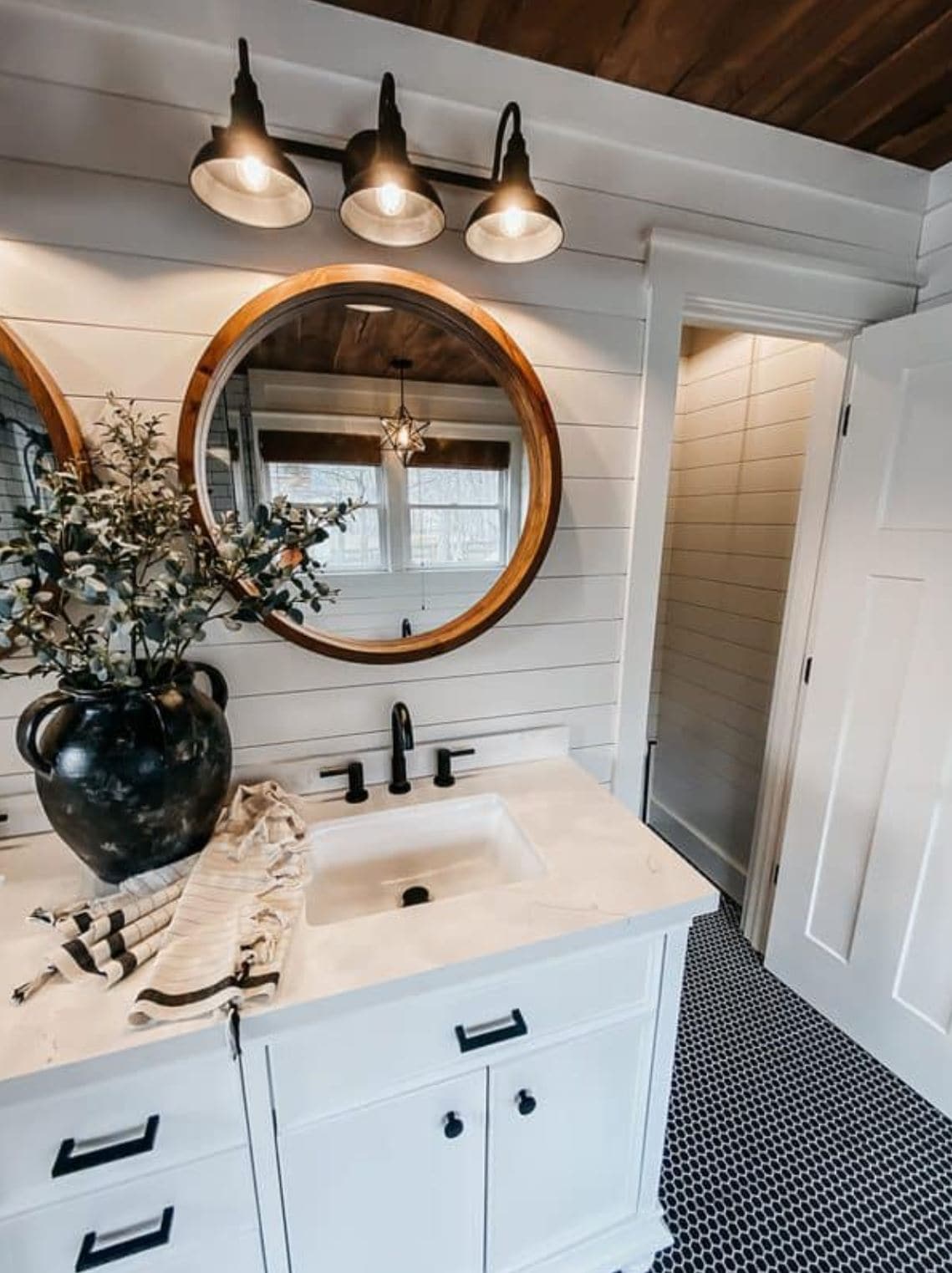 A black and white bathroom with shiplap paneling behind the vanity and up to the ceiling.