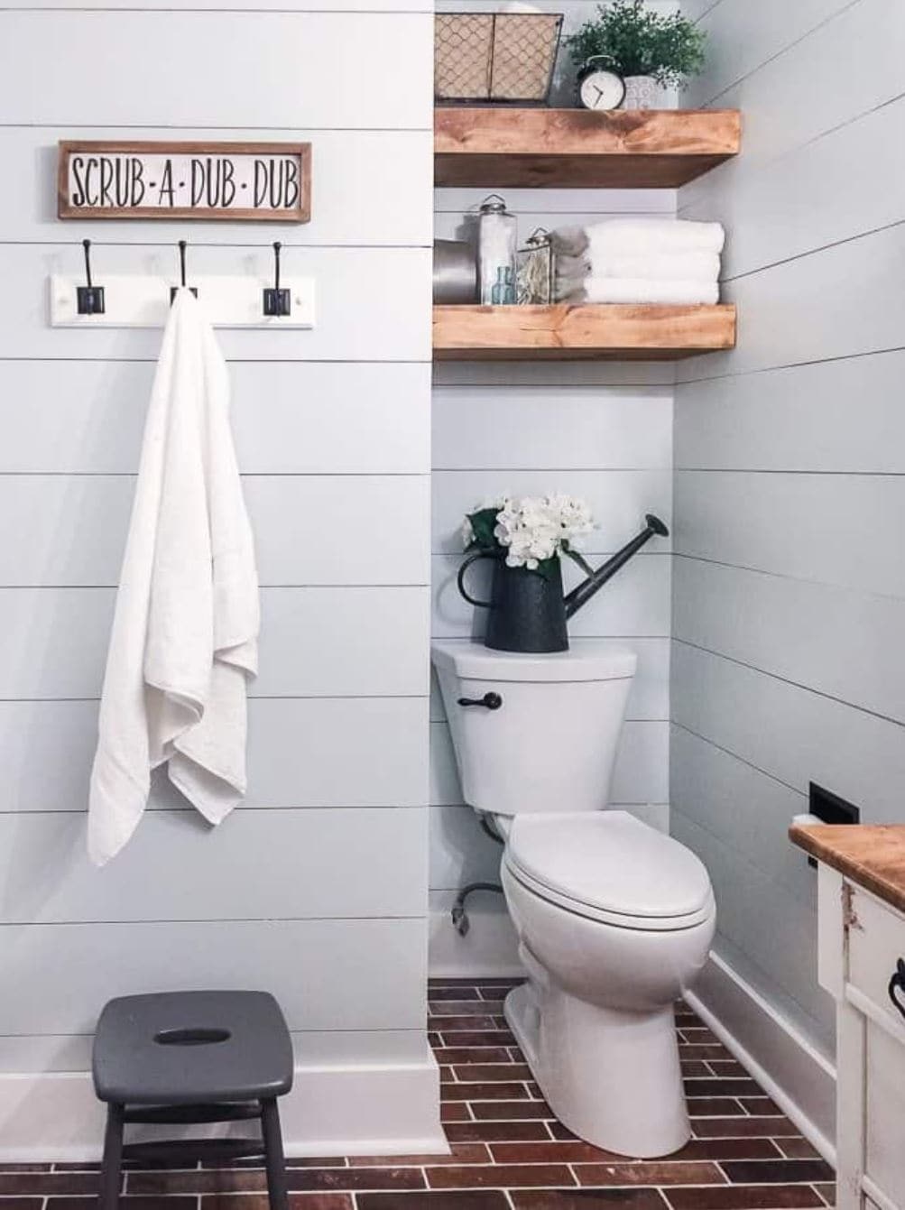 A bathroom remodel with shiplap walls, a wooden towel rack, and open shelving above the toilet area.