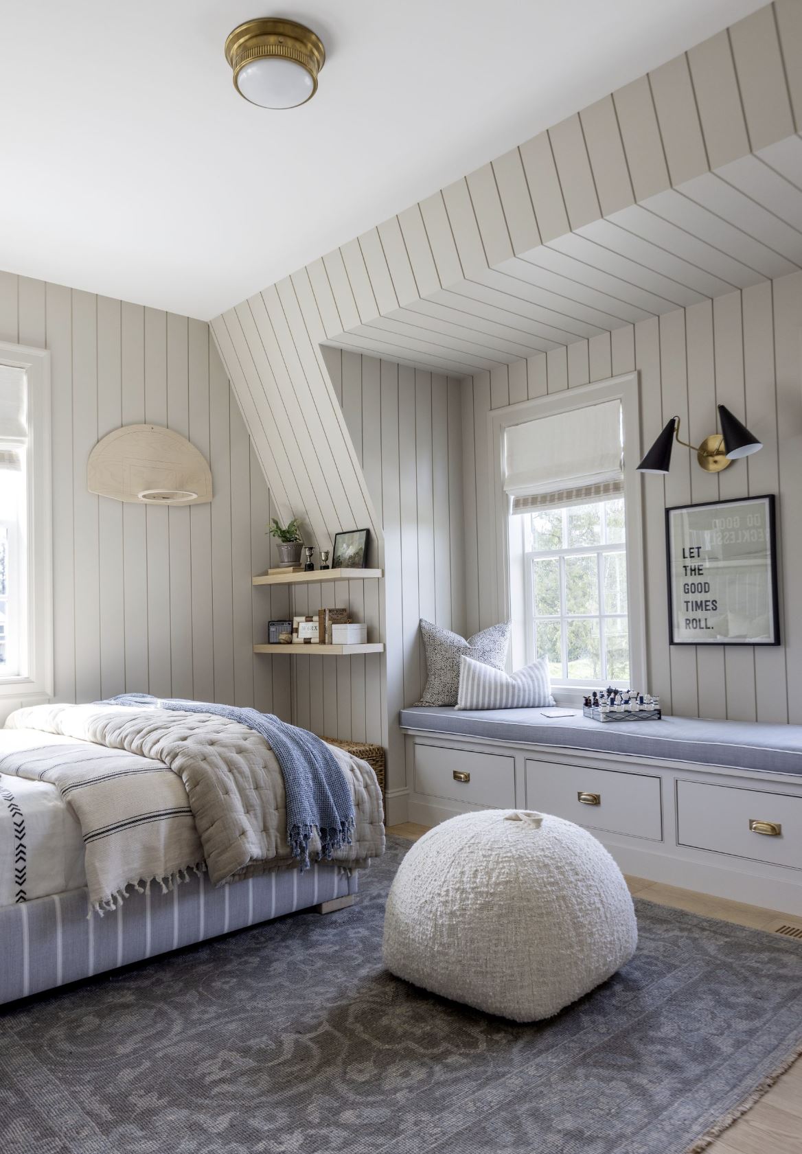 A boy's blue and beige bedroom with vertical beige shiplap and window seat.