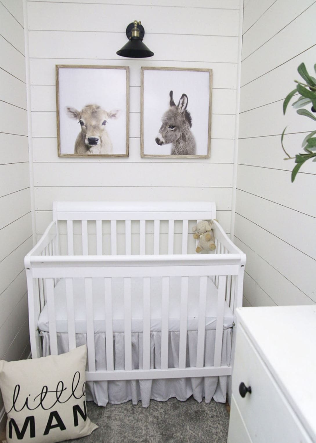 A baby nursery with mini crib, shiplap walls, and two baby animal prints above the crib.