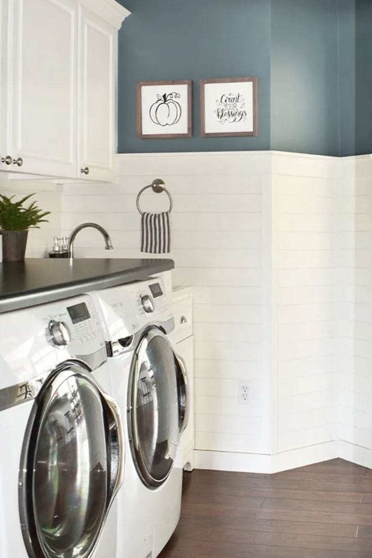 A farmhouse laundry room with blue walls and a half wall of horizontal shiplap.