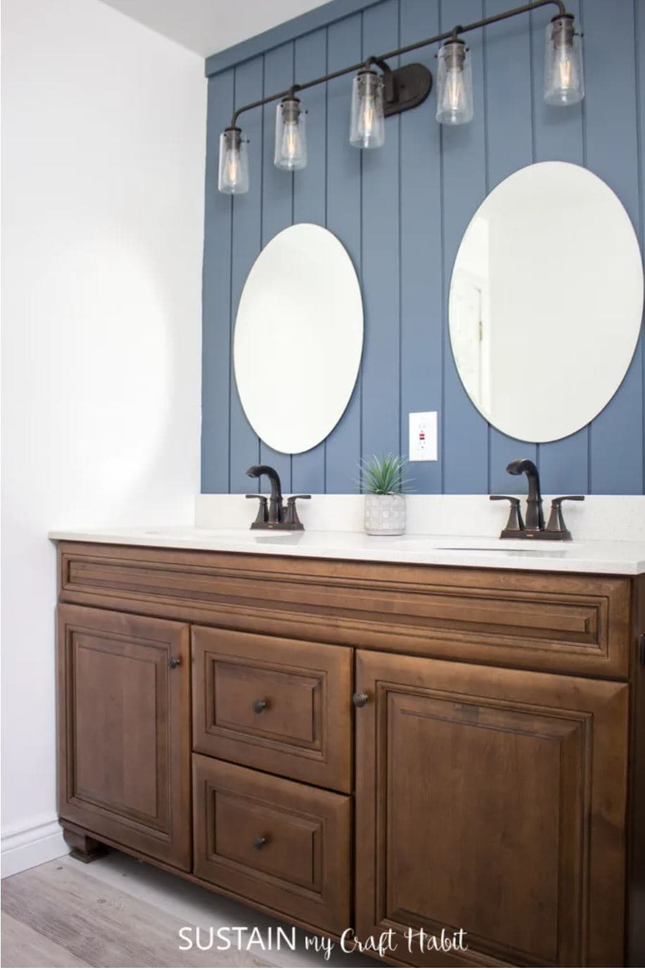 Vertical painted blue shiplap above a wooden bathroom vanity.