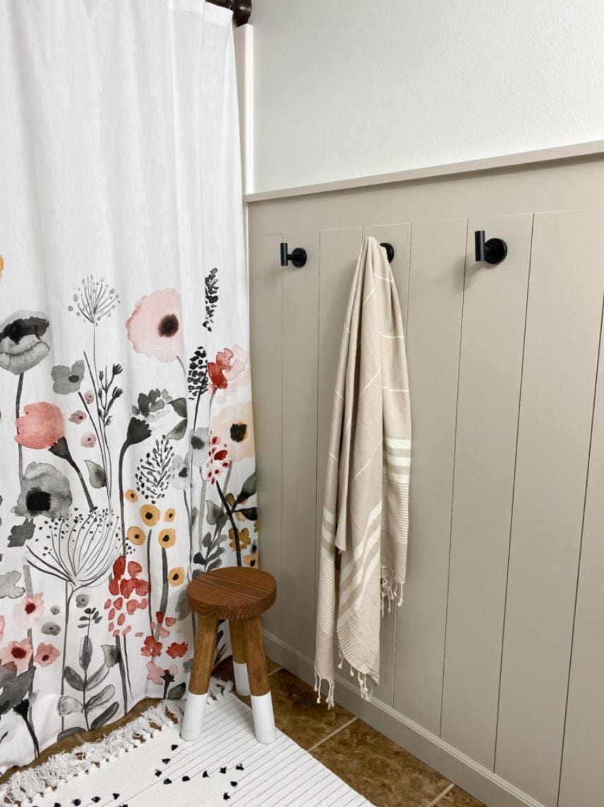 A vertical shiplap wall with towel hooks in a bathroom.