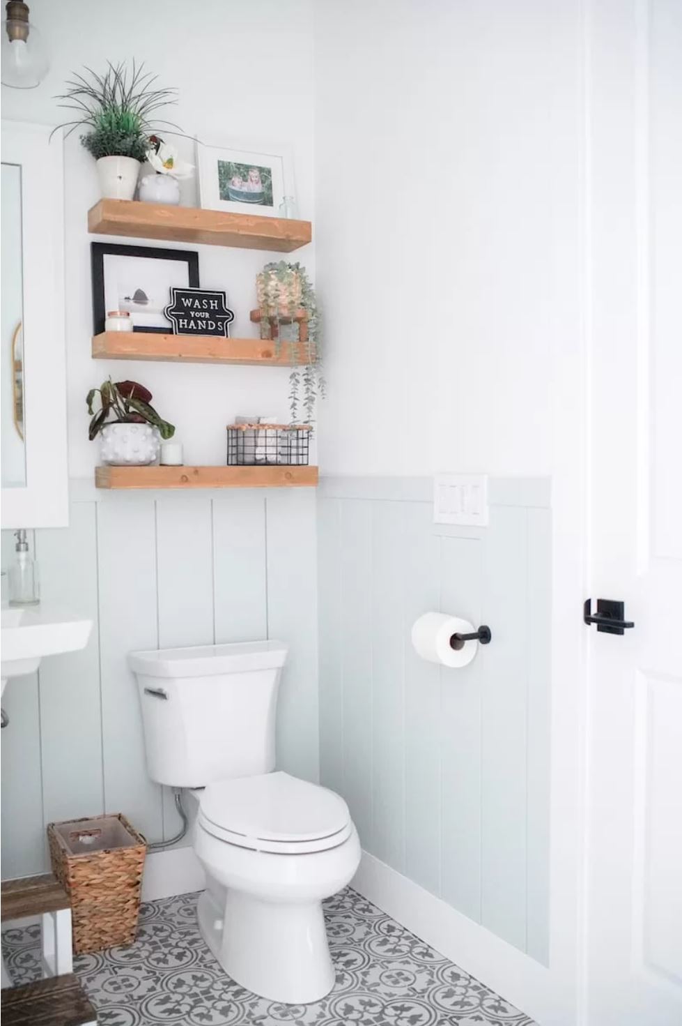 A farmhouse bathroom with stenciled flour, half-shiplap walls, and open shelving.