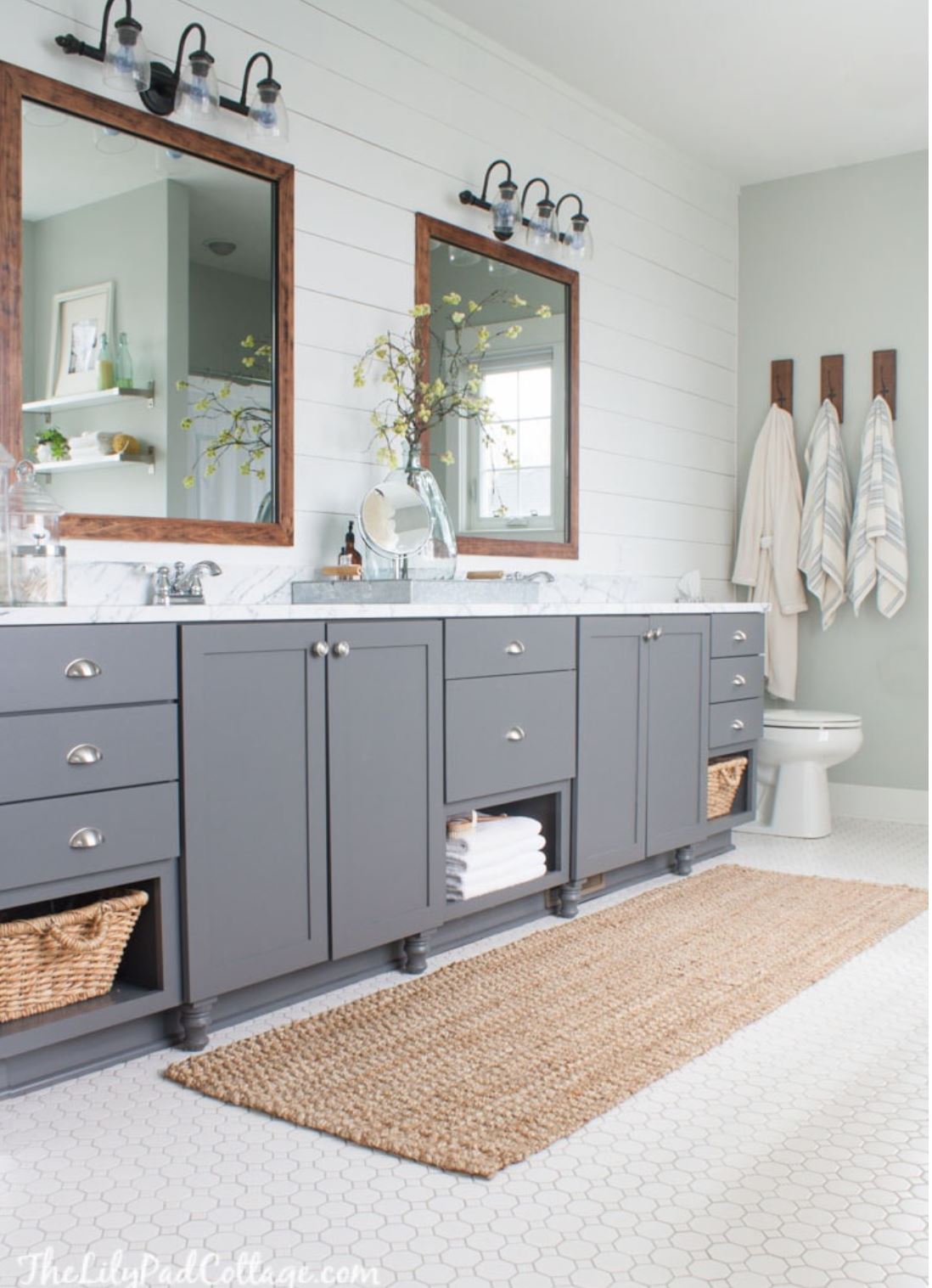 A gray and white bathroom with a double vanity and mirrors and shiplap accent wall.