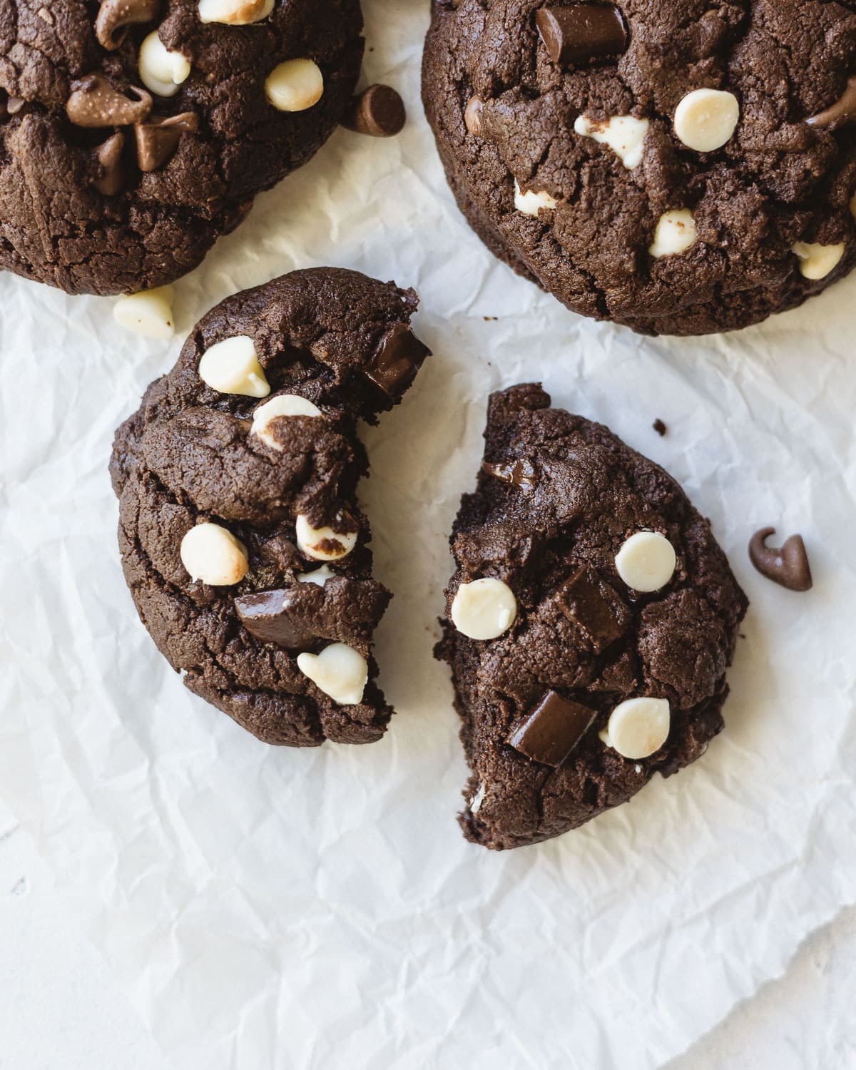A triple chocolate cookie split in half on a piece of crinkled parchment paper.