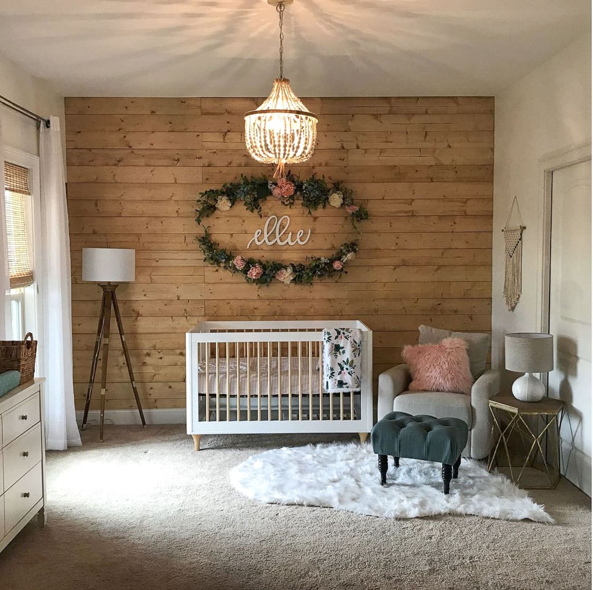 A farmhouse nursery for a baby girl with a rustic shiplap feature wall and floral baby name design.