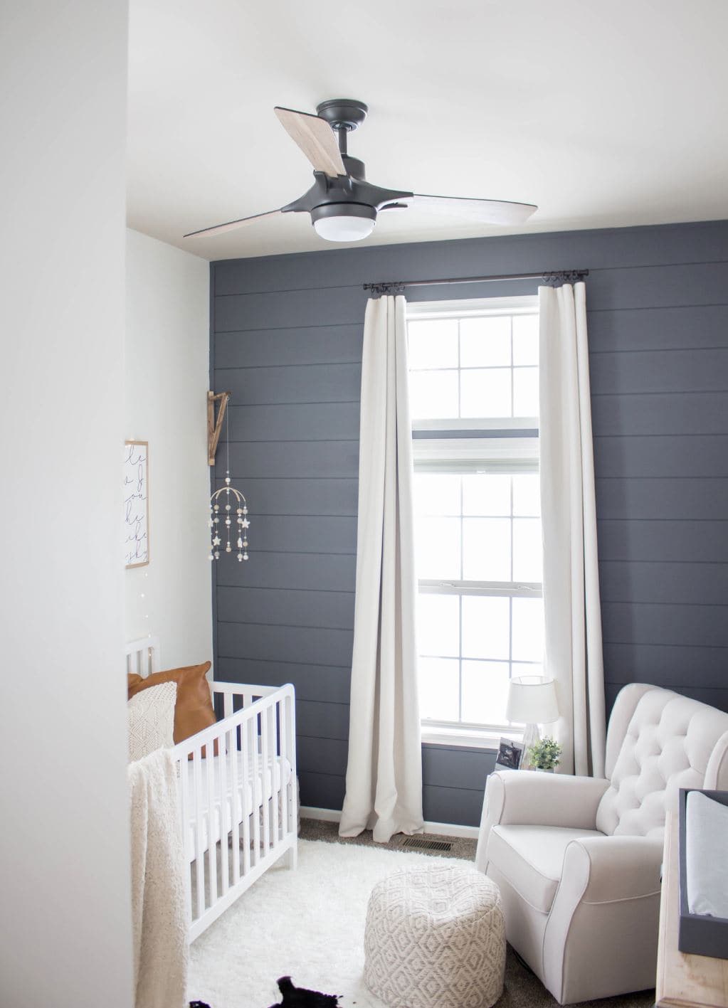 A baby boy nursery with white furniture and blue shiplap.