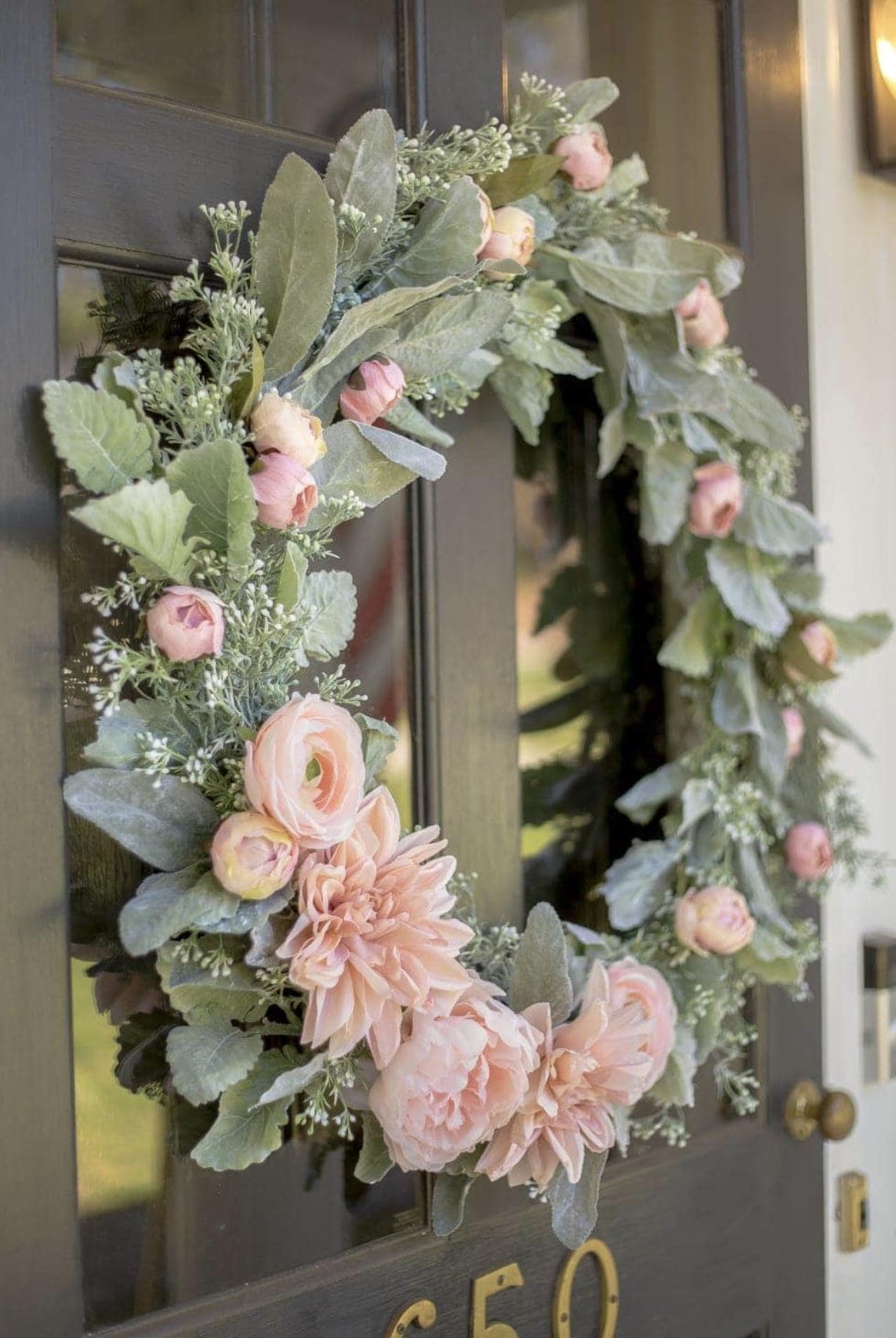 A blush and sage spring DIY wreath hanging on a front door.