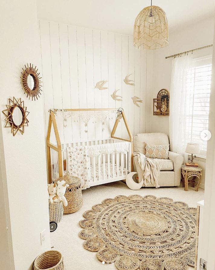 A boho baby girl nursery with vertical shiplap accent wall.