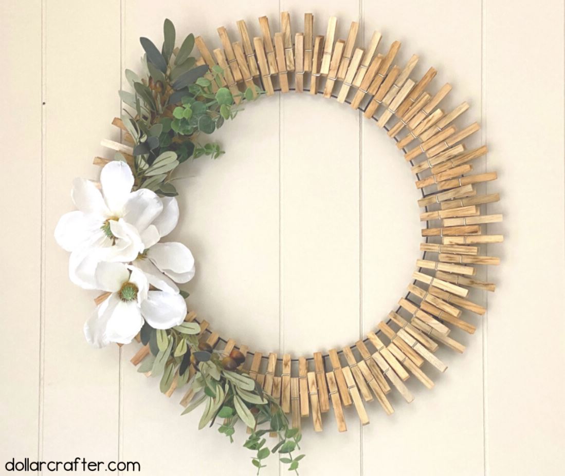 A wreath of clothespins and faux magnolia floral.