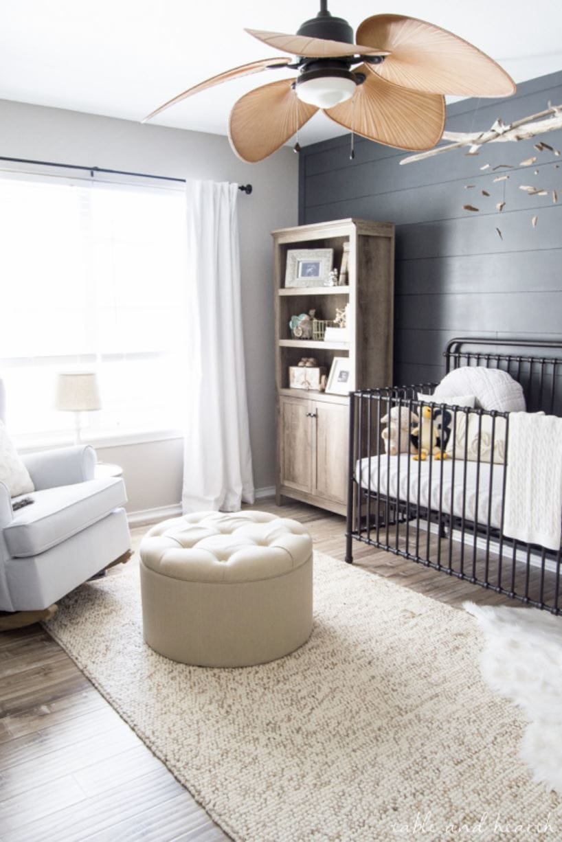 A neutral baby nursery with a horizontal dark blue shiplap wall.